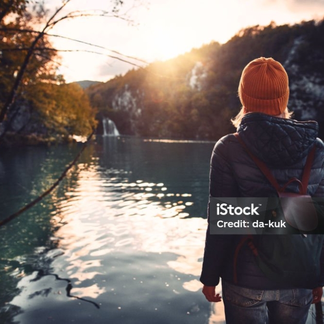 Woman tourist exploring Plitvice Lakes National Park at sunny autumn day. Croatia